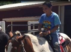 A boy is riding on the back of a horse.