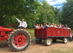 A group of people riding on the back of a red tractor.