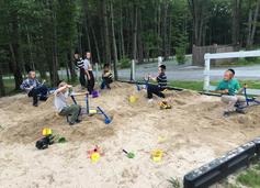 A group of people sitting on sand in the woods.