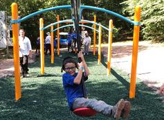 A boy is swinging on the playground equipment.